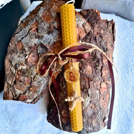 Påskelys lavet af naturlig bikage med et billede af Vor Frue af de Syv Sværd i flydende glas og et strikket kors