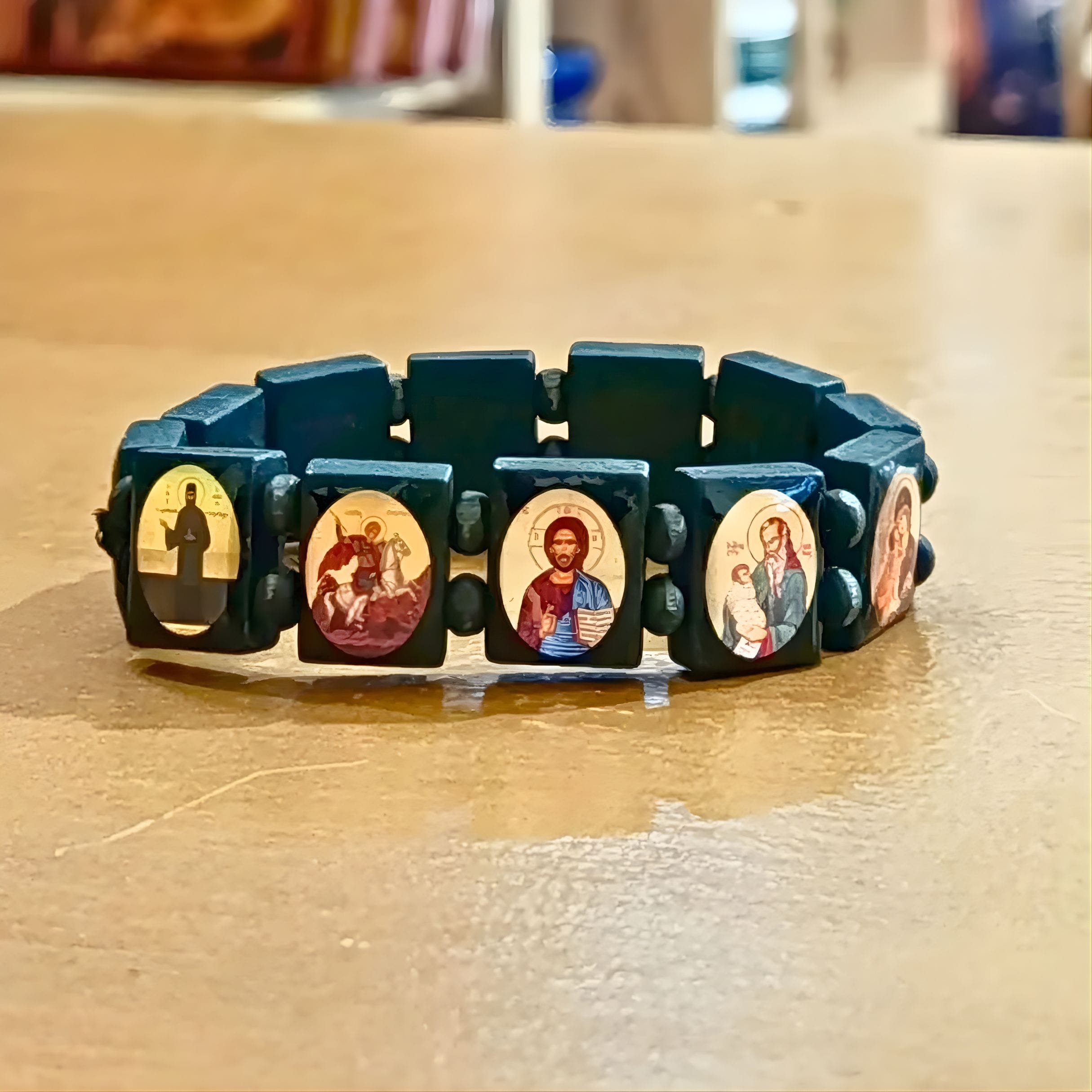 Κοντινή λήψη από χειροποίητο ορθόδοξο βραχιόλι με εικόνες αγίων σε μαύρες χάντρες, που δείχνει λεπτομερώς τις εικόνες του Αγίου Νικολάου, της Παναγίας, του Χριστού και του Αγίου Γεωργίου